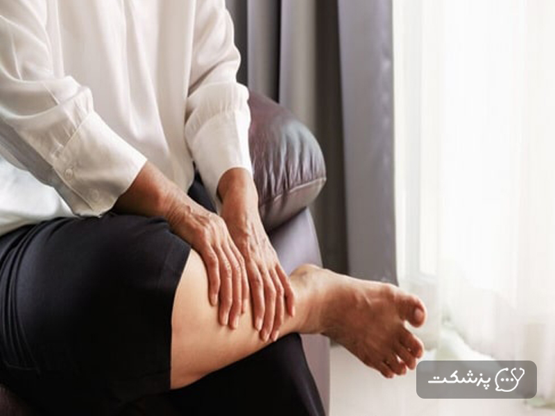 فردی در حال ماساژ دادن پای خود روی مبل